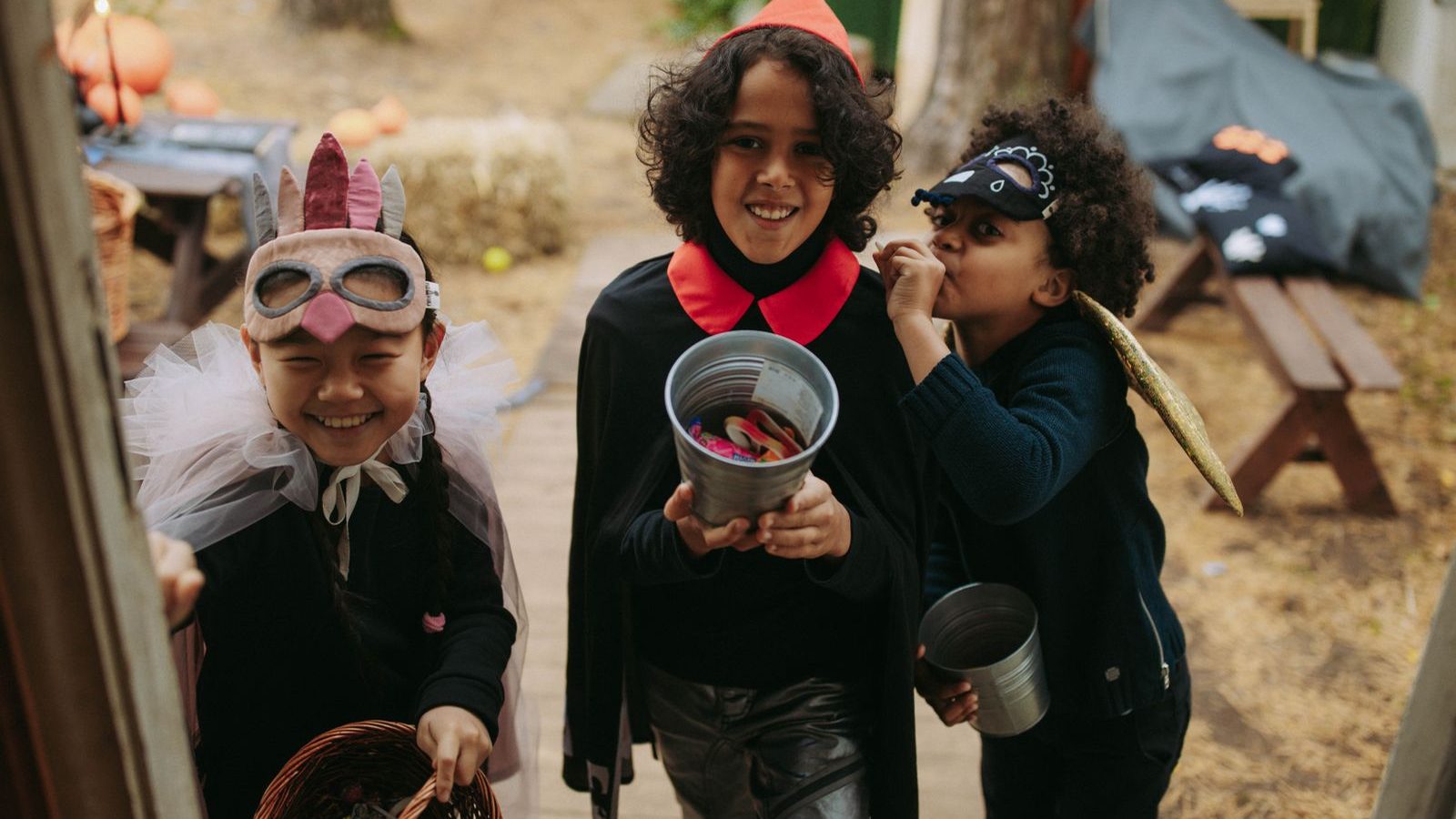 Drie verklede kinderen met snoepemmers gaan langs de deuren op Halloween