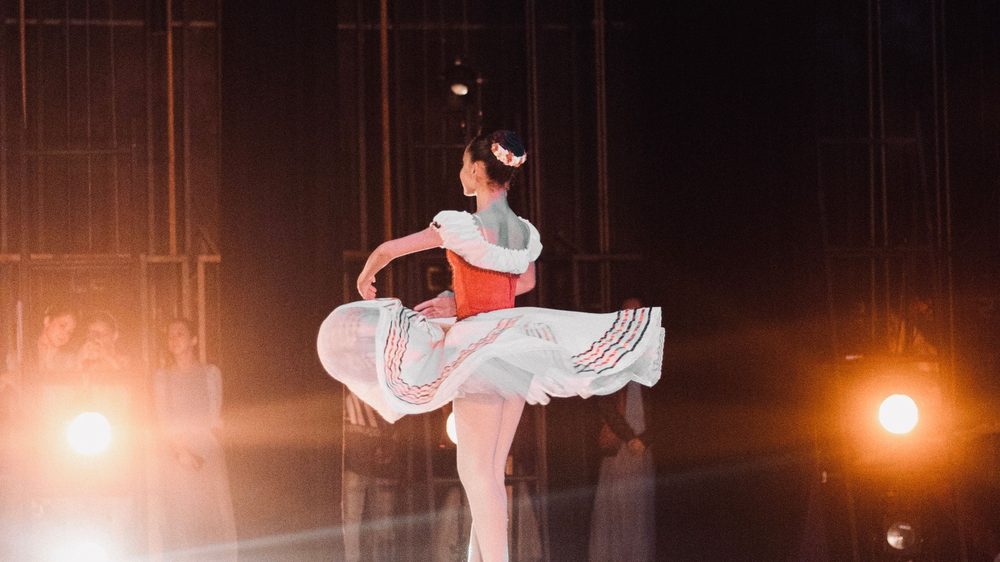 Balletdanseres in een wit tutu draait in het licht van de schijnwerpers op een podium